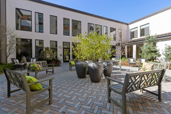 A courtyard with benches facing potted plants in the middle.