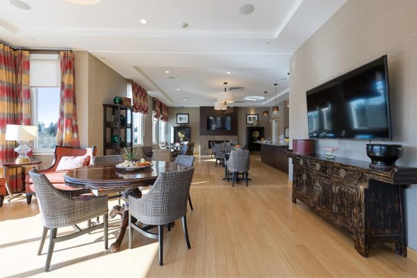 A seating area with tables, chairs, and a large television.