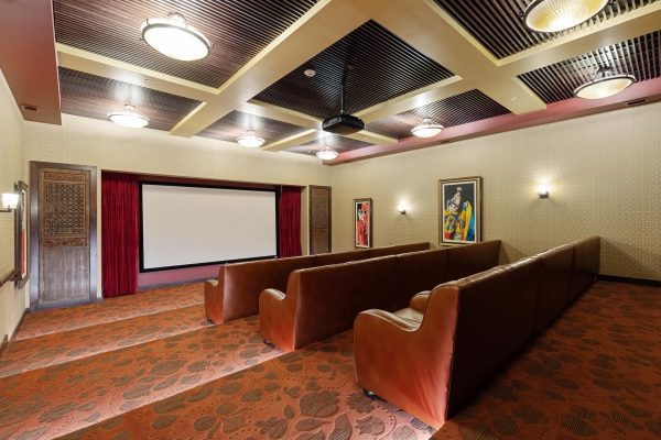 A movie theatre room with three rows of seats and a large screen.