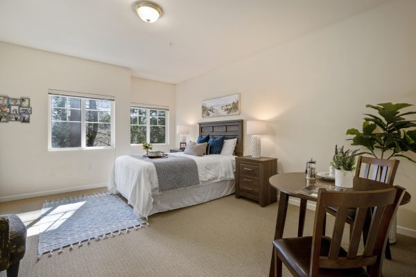 A bedroom with a table, chairs, and a large window.