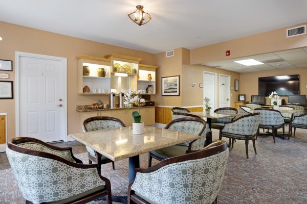 An eating area with tables, chairs, a coffee station, and a television.