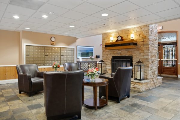 The inside of the main entrance at Aegis Lodge, with chairs, a fireplace, and mailboxes.