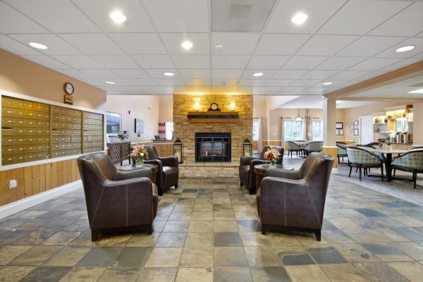 The inside of the main entrance at Aegis Lodge, with chairs, a fireplace, and mailboxes.