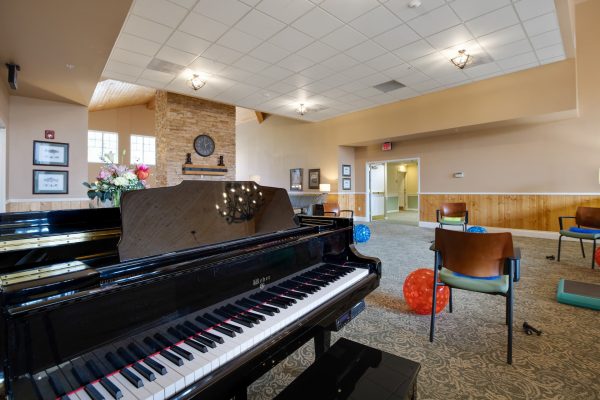 A piano with chairs and exercise balls in the background.