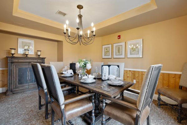 A dining table and chairs with a chandelier above.