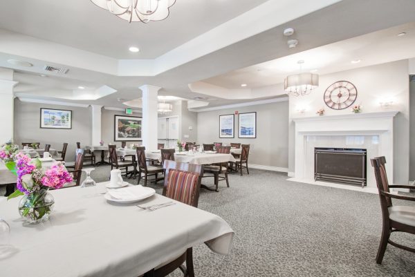 A formal dining area with tables, chairs, and a fireplace