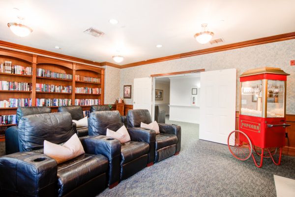 A movie theater room with large armchairs and a popcorn machine