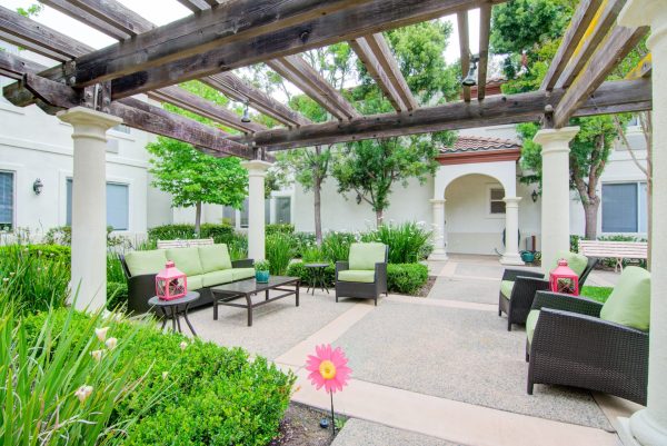 A partially covered outdoor seating area with lots of greenery in the background