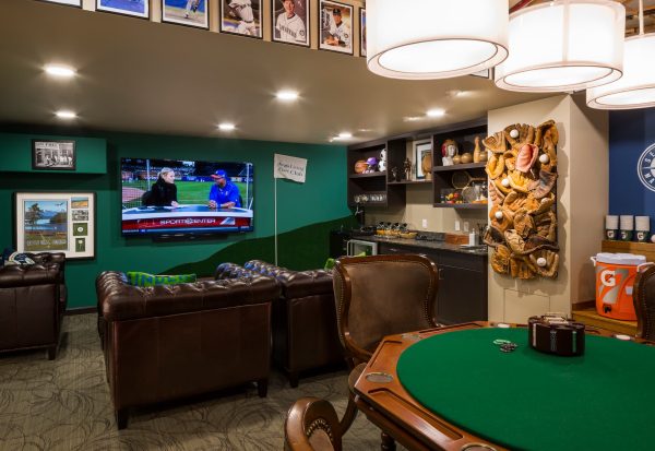 A sports-themed room with a card table, chairs, a couch, and a television