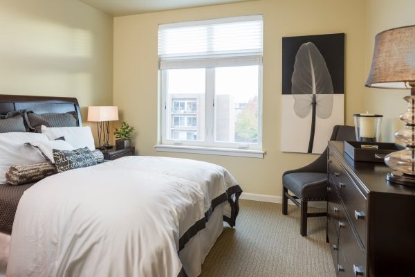 A bedroom with a cozy bed, dresser, and window