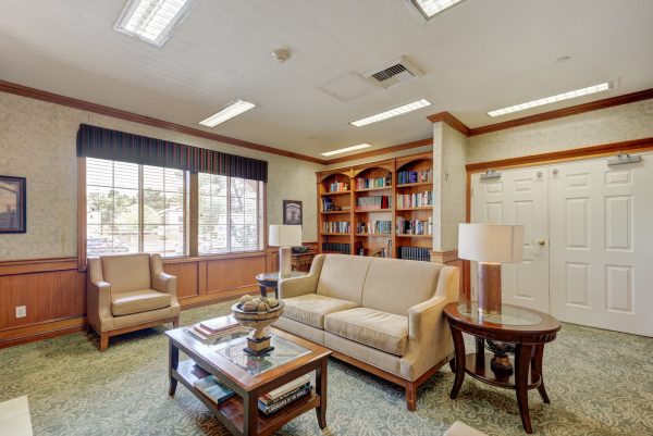 A library with a built-in bookshelf, a couch, a coffee table, and an armchair