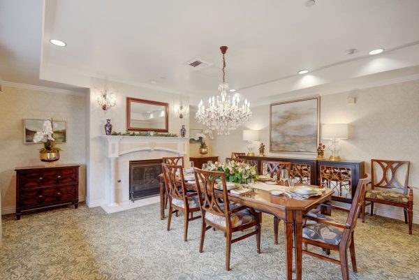 A large brown dining table and chairs with a fireplace in the background