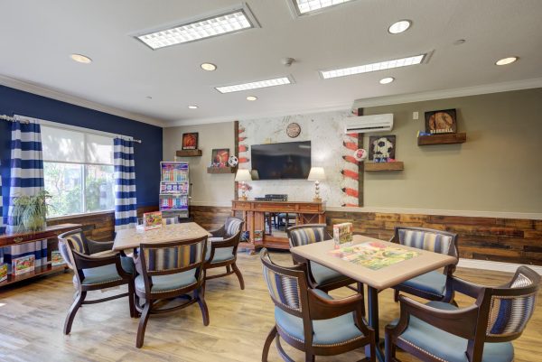 A games room with tables and chairs, puzzles, and a television