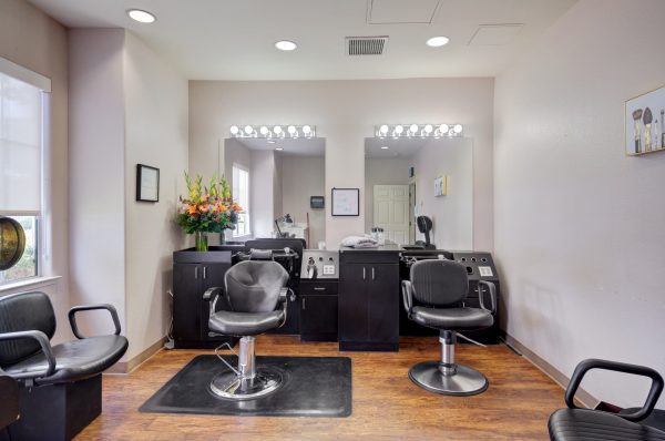 A hair salon with two salon chairs and sinks, two mirrors, and a hooded dryer