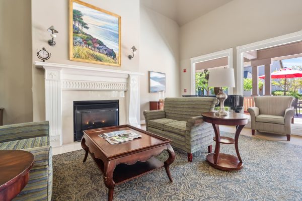 A bright, welcoming seating area with two couches and a table in front of a fireplace with a painting above it.