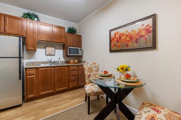 A small kitchen with brown cabinets and a table and a chair.