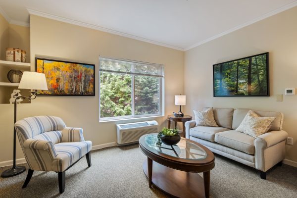 A room with a large window, a chair, and a table.