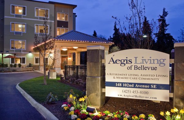 The Aegis Living Bellevue sign, at dusk, with Aegis Living in the background.