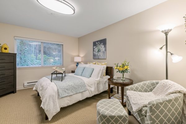 A bedroom with a bed, armchair, and dresser