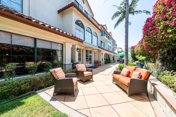 An outdoor seating area with pink flowers and palm trees in the background