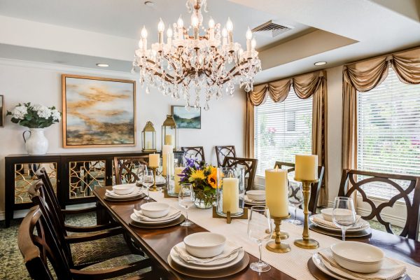 A large dining table with an opulent chandelier hanging above