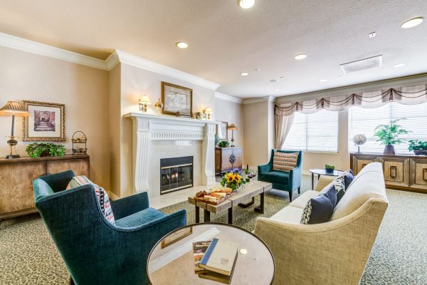 A small seating area with a beige couch, green chairs, and a fireplace