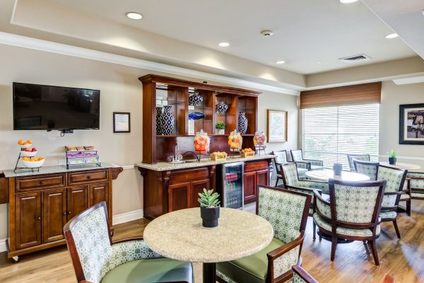 A small dining area with tables, chairs, and a kitchenette in the background