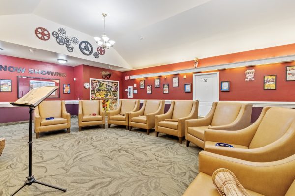 A group of brown armchairs facing a television and a guitar