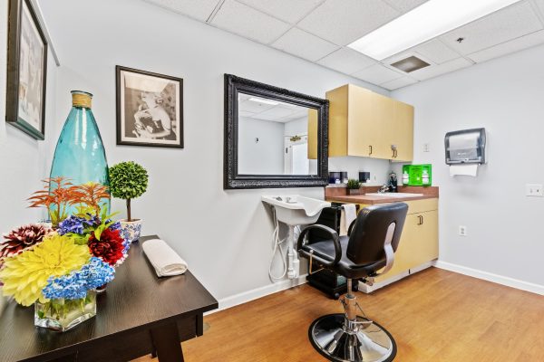 A small barbershop with one styling chair, a sink, and a table