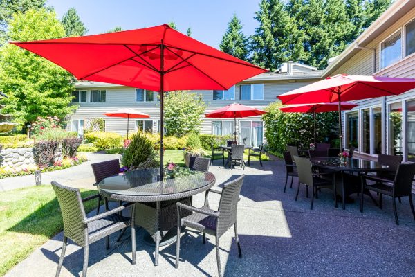 An outdoor seating area with tables, chairs, and red umbrellas