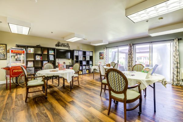 A games room with tables, chairs, shelves, and a popcorn machine