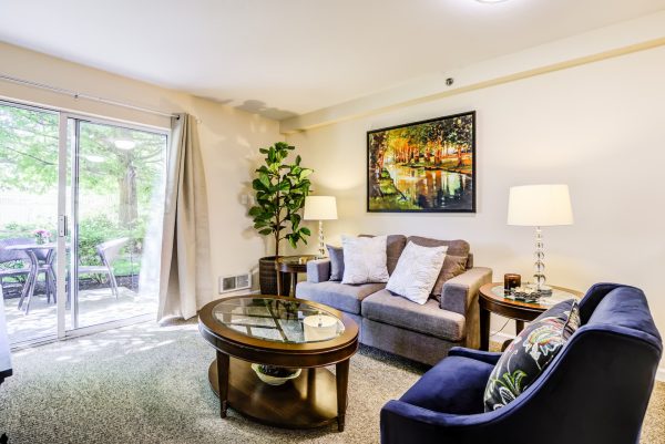 A living room with a couch, armchair, coffee table, and sliding glass doors