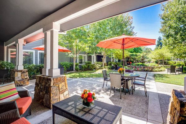 A covered outdoor seating area with a patio set in the distance