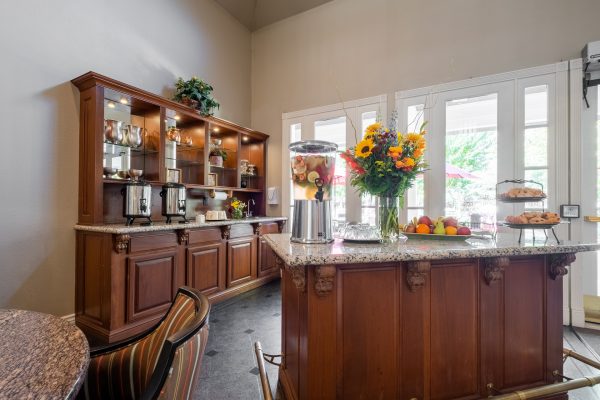 A coffee and breakfast corner with food, water, and flowers on the counter