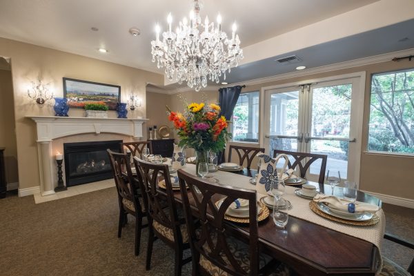 A large dining table with a chandelier overhead and a fireplace at the back