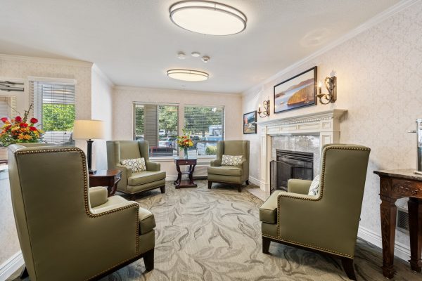 A living area with four green armchairs and a fireplace