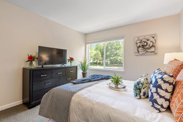 A bedroom with a large bed, dresser, and television