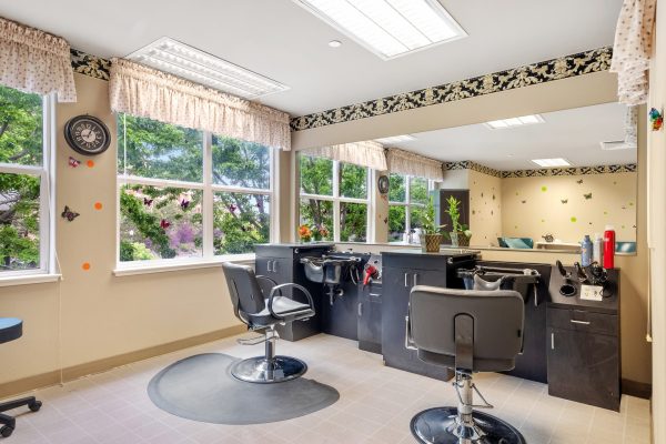 A hair salon with two salon chairs, two hair washing stations, and a large mirror