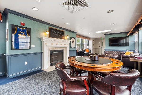 A games room with a large card table, fireplace, and sport jersey on the wall