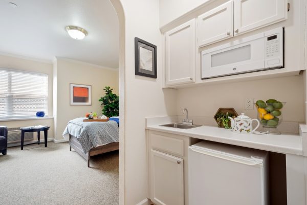 A kitchenette with a bedroom in the background