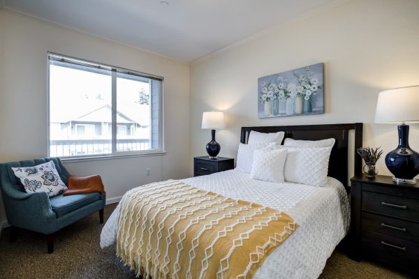 A bedroom with a bed, blue armchair, and window