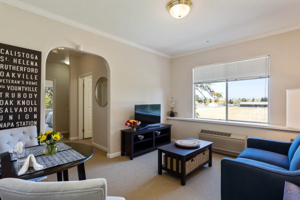 A small living area with a couch, table and chairs, television, and archway