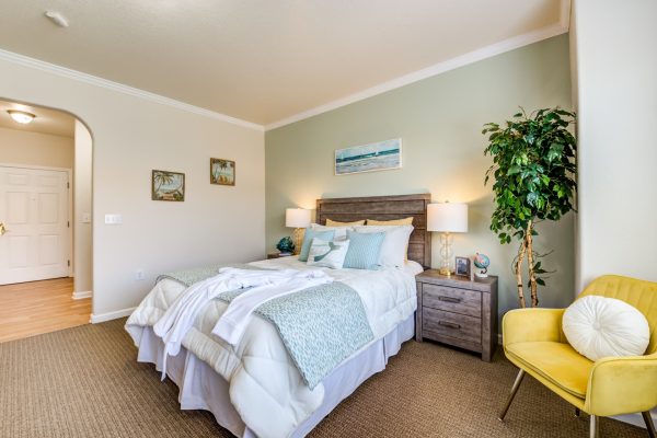 A bedroom with a bed, nightstands, and a yellow chair