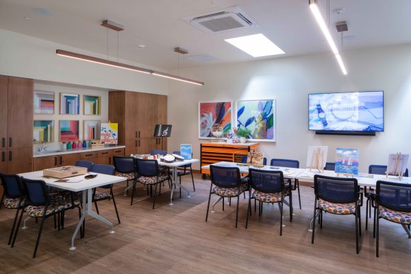 An art room with tables and chairs, painting supplies, and a television