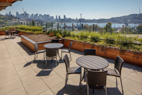 A view of the patio with tables, chairs, and Lake Union in the background