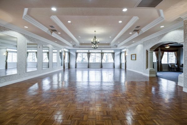 A large empty room with mirrors on the wall and large windows in the back