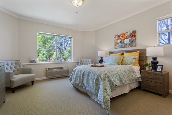 A bedroom with a bed and large chair in the corner