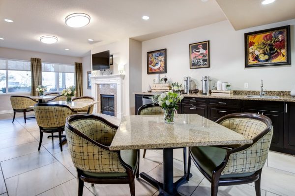 A small dining area with tables, chairs, fireplace, and large windows