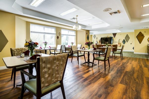 A dining area with tables, chairs, and large windows.