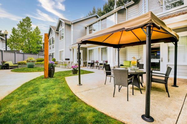 An outside view of Aegis Living with a covered table and chairs.